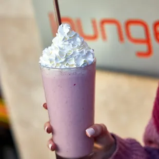 a woman holding a pink drink