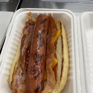 Hot dog  with ketchup and bacon strips