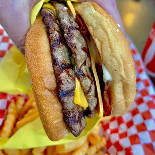 a hand holding a hamburger and fries