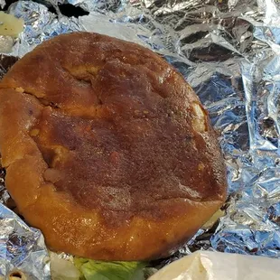 Bottom of pretzel bun drenched in burger grease!