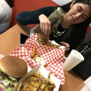 a woman eating a cheeseburger and fries
