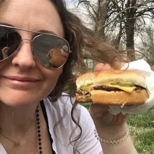 a woman in sunglasses holding a hamburger