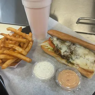 Philly cheesesteak with a side of ranch and chipotle sauce.
