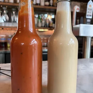 two bottles of sauce on a counter