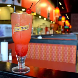 a red drink with a cherry garnish