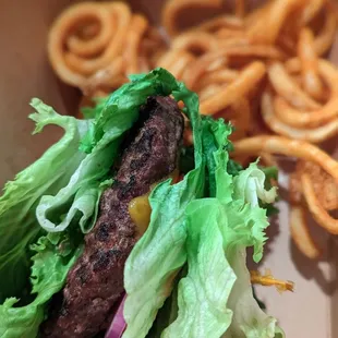 a burger with lettuce and onion rings