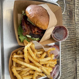 Single burger with avocado, bacon and lettuce with barbecue on the side. Fries as well