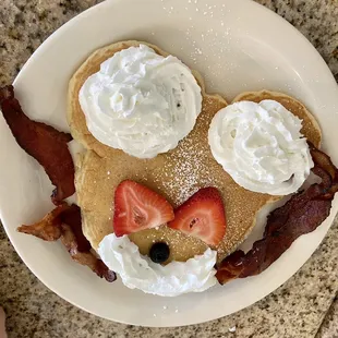a plate of pancakes with bacon and strawberries
