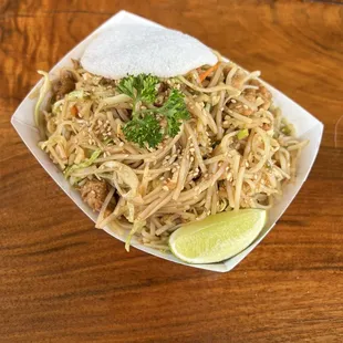 a plate of noodles with a lime wedge