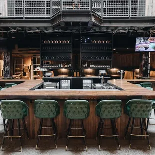 a bar with green chairs and a wooden counter