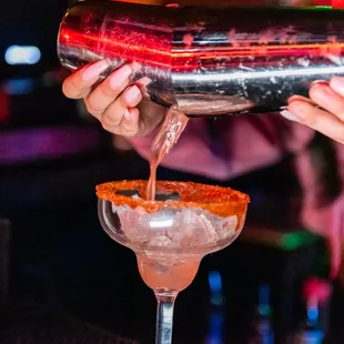 a bartender pouring a drink into a glass
