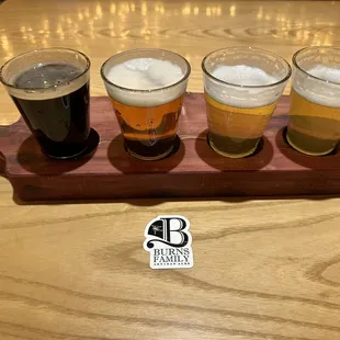 a flight of beers on a wooden serving board