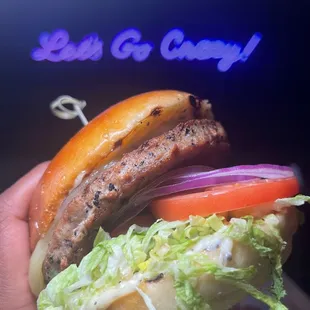 a hand holding a sandwich with lettuce and tomatoes