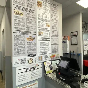 a restaurant counter with a menu on the wall