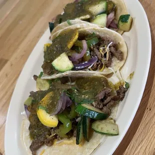 three tacos on a white plate