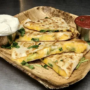 three quesadillas on a wooden plate