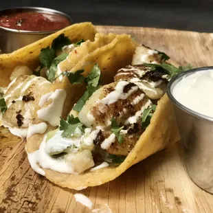 two tacos with sauce on the side