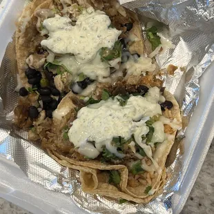 Two Carnitas tacos to go in corn tortillas.