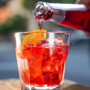 a person pouring a drink into a glass