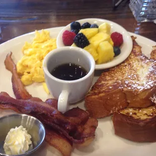 Scrambled eggs, bacon, fruit, and French toast.