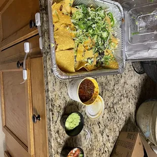 a pan of nachos and a container of guacamole