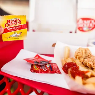 a person holding a packet of chicken and fries