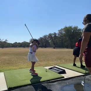 a little girl playing golf