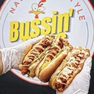 a hand holding two hot dogs