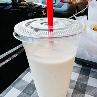 a plastic cup with a straw on a checkered tablecloth