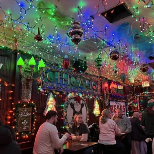 people sitting at a bar with christmas lights on the ceiling