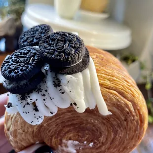 a person holding a pastry with oreo cookies on top