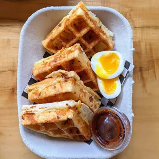 Pao de Queijo Waffle - Bacon, Egg, &amp; Cheddar. $9. Stuffed with crispy bacon and cheddar, topped w/ soft-boiled egg. Side of guava jelly.