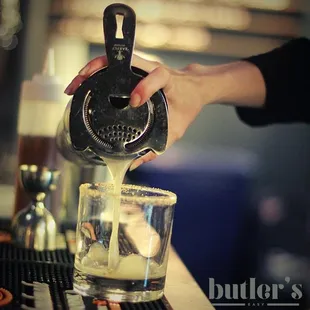 a person pouring a drink into a glass