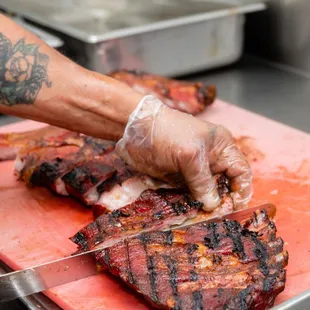 a person cutting up a steak on a cutting board