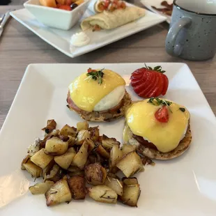 Eggs Benedict with potatoes, and in the background is breakfast burrito with the fruit!