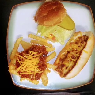 a plate of food including a chili dog, cheese fries, and pickle