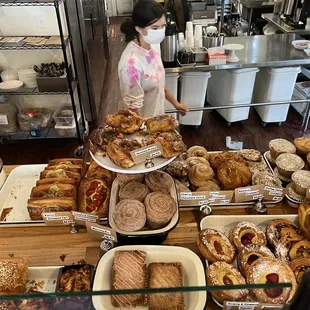 a woman standing in front of a display of baked goods