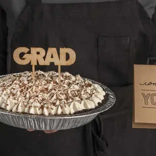 a person holding a cake with a graduation cake topper