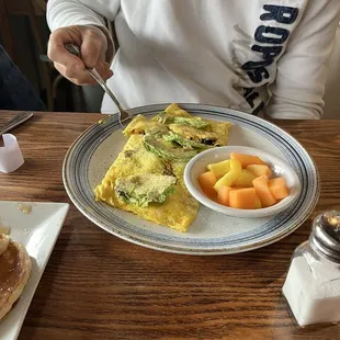 spinach/ avocado/ bacon / cheese omelette with side of fruit The omelettes come with choice of 2 sides  ( he chose fruit and pancakes)