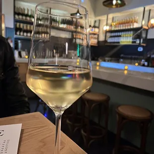 a glass of white wine on a bar