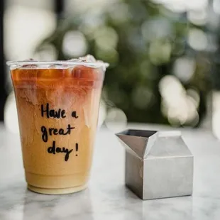 a glass of iced coffee and a small house