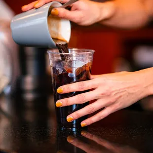 a person pouring a drink into a glass