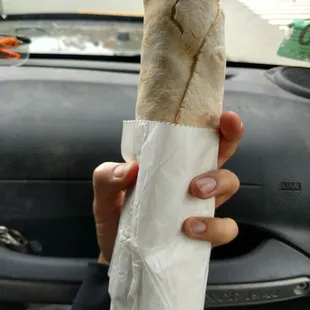 a person holding a burrito in their hand