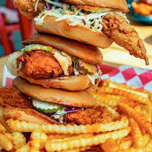 a stack of fried chicken sandwiches and french fries