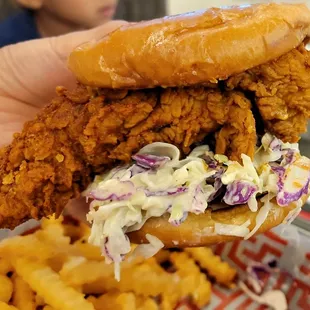 a fried chicken sandwich with coleslaw and fries