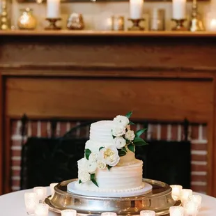 a wedding cake on a silver platter surrounded by candles