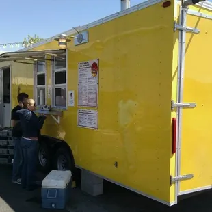 two people standing in front of a food truck