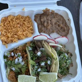 Taco plate with "al pastor", "guisada", "chickin", rice, and beans