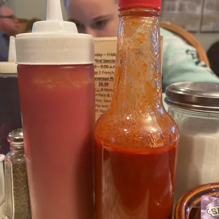 a bottle of hot sauce and a container of ketchup
