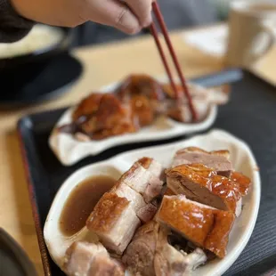 a plate of meat with chopsticks